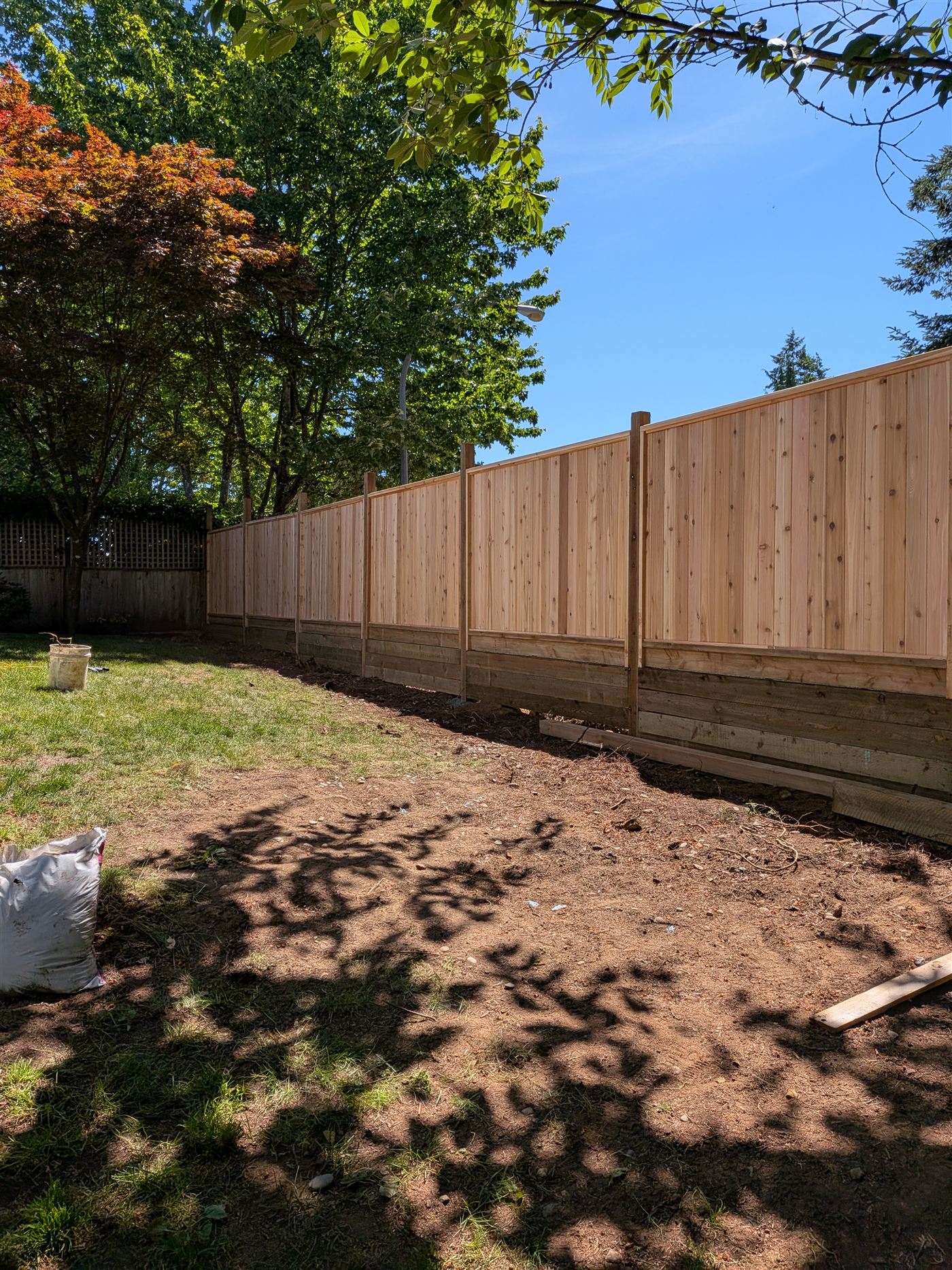 Board-on-board western red cedar fence with capped posts, newly installed on a graded lot