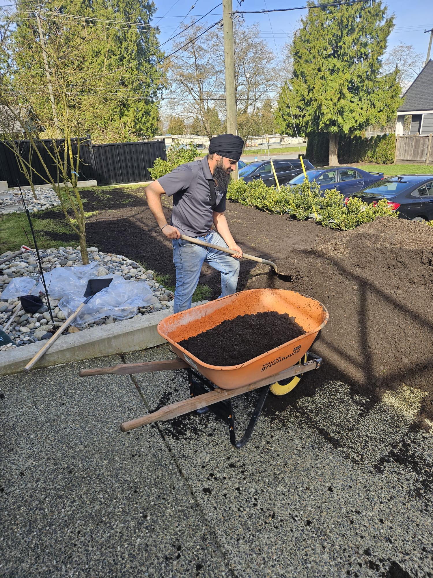 Pavneet Singh, the founder of Ironwood Grounds, spreading fresh compost while planting a new boxwood bed